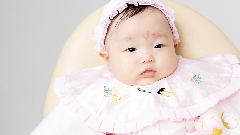 お宮参りで赤い産着を着た女の子の赤ちゃん。鞠と牡丹の柄。京都・スタジオクレアーレにて撮影